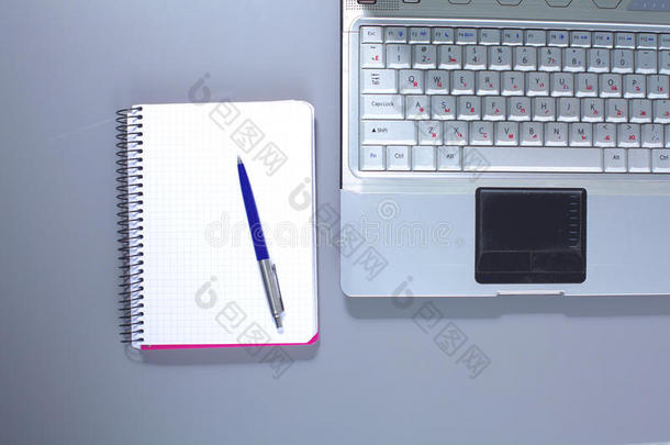 一本笔记本，笔记本电脑，钢笔，白纸文件放在办公桌后面的白色盲人桌子上