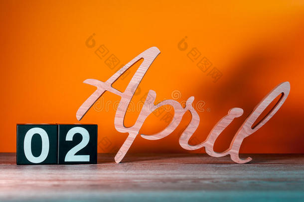 四月<strong>二日</strong>。每月的第二天，桌子上有橙色背景的木制日历。春季概念
