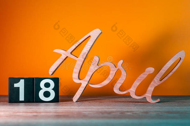 四月十八日。 <strong>每月</strong>18日，每日木制日历在桌子上，橙色背景。 春季时间概念