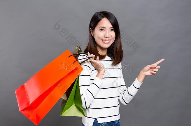 亚洲年轻女子拎着购物袋，手指向上