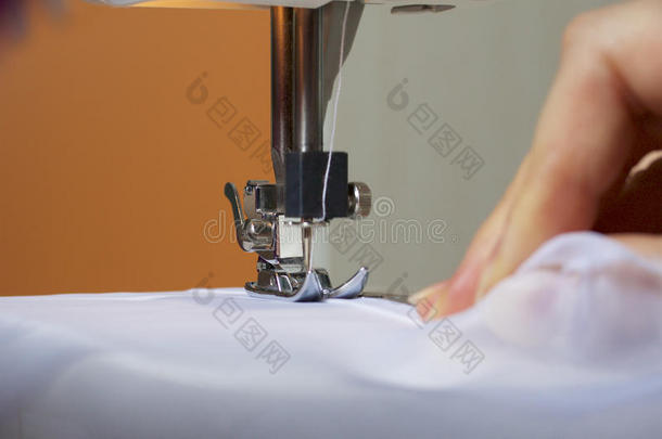 一个女人在缝纫机上工作。 她把窗帘缝在窗户上