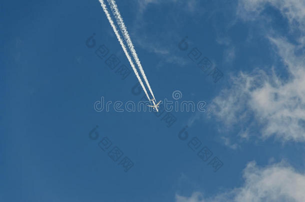 带着反应轨迹的飞机带着云层飞越蓝天