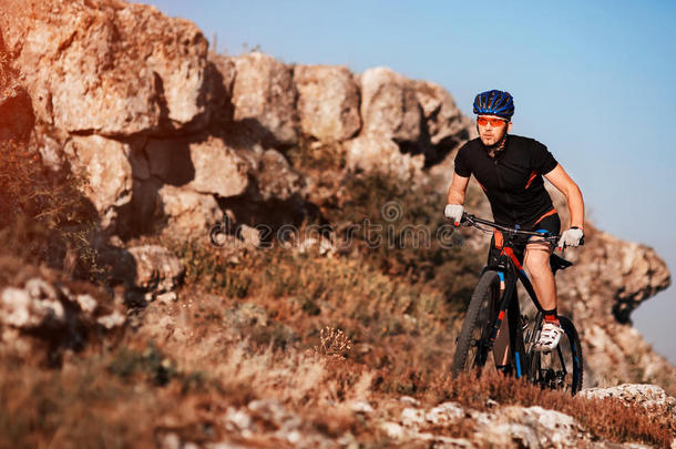 穿着黑色运动服的<strong>骑</strong>车人在岩石小径上<strong>骑</strong>自行车。 极限运动概念。 文本的空间。