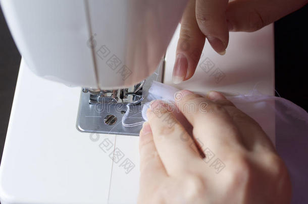 一个女人在缝纫机上工作。 她把窗帘缝在窗户上