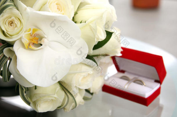美丽的婚礼花束玫瑰和兰花和红色天鹅绒盒与黄金和白金结婚戒指