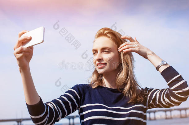 美丽的年轻女子，金发，在户外使用智能<strong>手机</strong>和快速4G互联网连接，同时站在铆钉