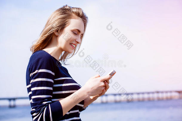 美丽的年轻女子，金发，在户外使用智能<strong>手机</strong>和快速4G互联网连接，同时站在