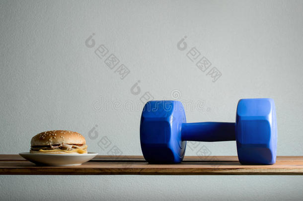 哑铃和汉堡在木桌饮食，锻炼体重LOS