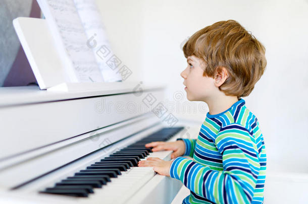 漂亮的小男孩在客厅或音乐学校弹钢琴
