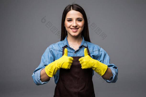 干净的女人竖起大拇指，在灰色的背景上戴着黄色的手套