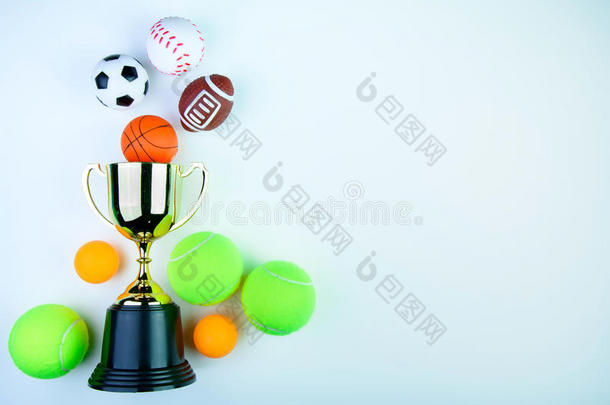 金色奖杯，足球玩具，棒球玩具，乒乓球，网球，篮球玩具和橄榄球玩具隔离在白色背景上