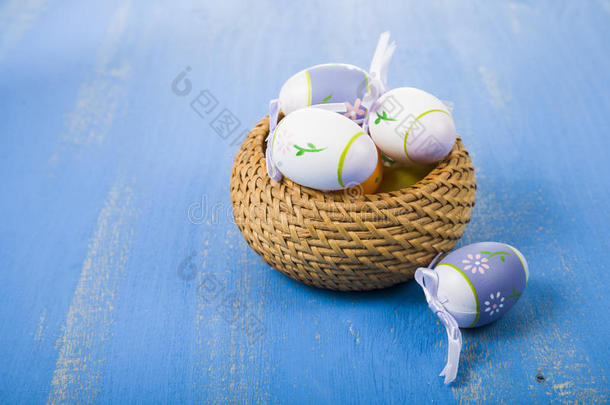 篮子里的复活节鸡蛋放在蓝色的木桌上。