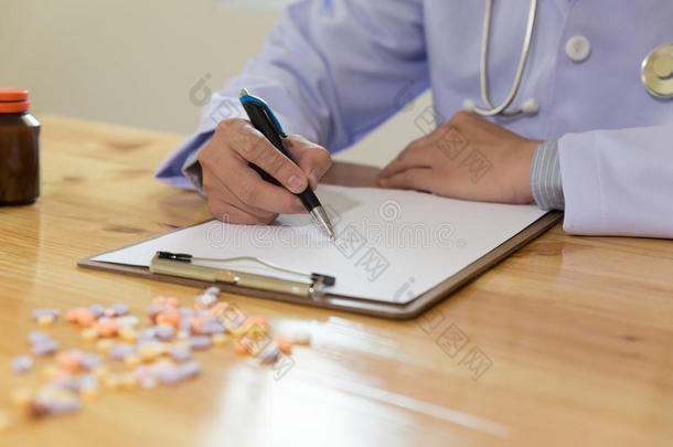 医生在医疗办公室诊所书写RX处方，办公桌上有药物