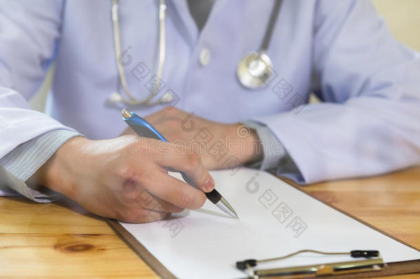 医生在办公桌上的医疗办公室诊所书写RX处方，带剪贴板的听诊器