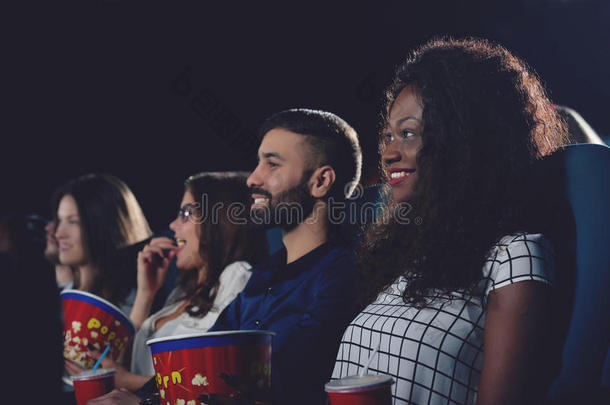 卷曲的非洲女孩牙齿微笑，在电影院看电影。