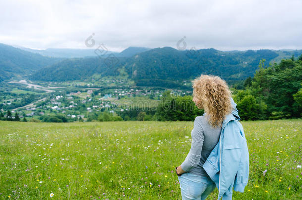 一个年轻的女孩站在多云天气的山顶上<strong>欣赏风景</strong>