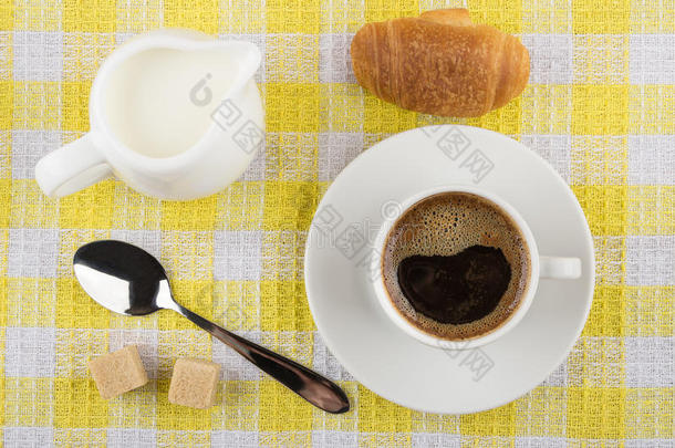 咖啡杯，牛奶罐，牛角面包，糖和餐巾上的勺子