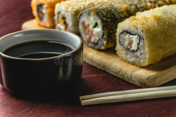 用酱油和筷子夹在木盘上的寿司卷