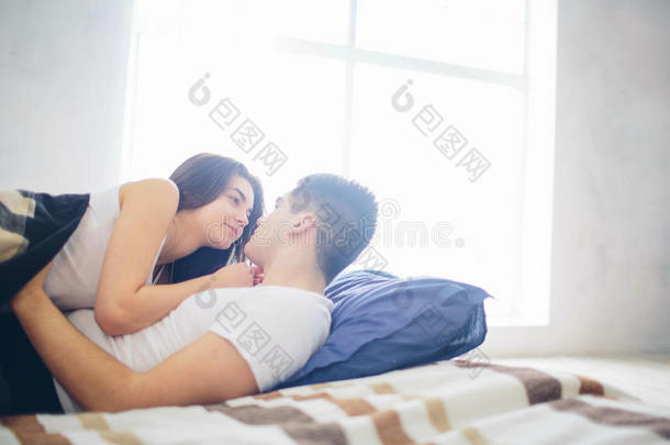 一对恩爱的夫妇躺在床上。 明亮舒适的卧室。 家庭的安慰和爱