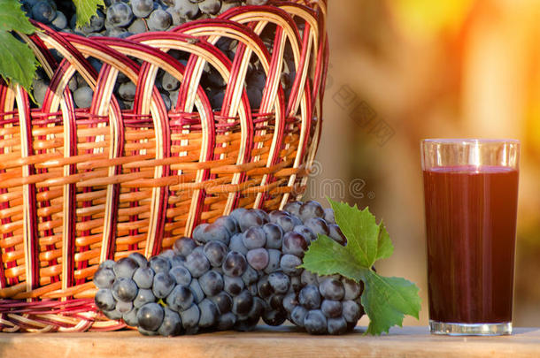 一串葡萄和一杯葡萄汁，一个柳条篮子，在阳光下放着葡萄
