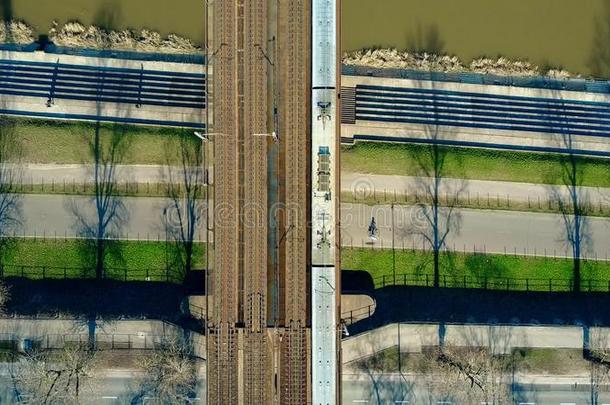 空中拍摄的旅客列车在铁路桥上<strong>跨越</strong>河流和自行车道，顶部的景色。 生态学