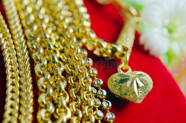 金项链96.5%泰国黄金等级与鲜花和独特的金心吊坠穿上红色法兰绒布背景