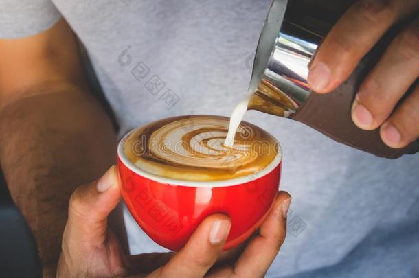 咖啡师的手倒牛奶，用红色的杯子做咖啡拿<strong>铁艺</strong>术。