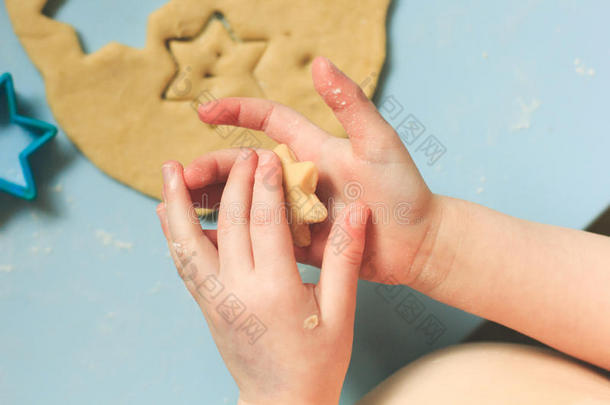 小男孩把一个明星饼干切割机压在糖饼干面团里。 上图。 一颗心和一颗星星在小手中