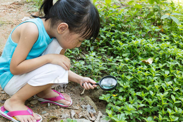 亚洲中国小女孩用放大镜探索草