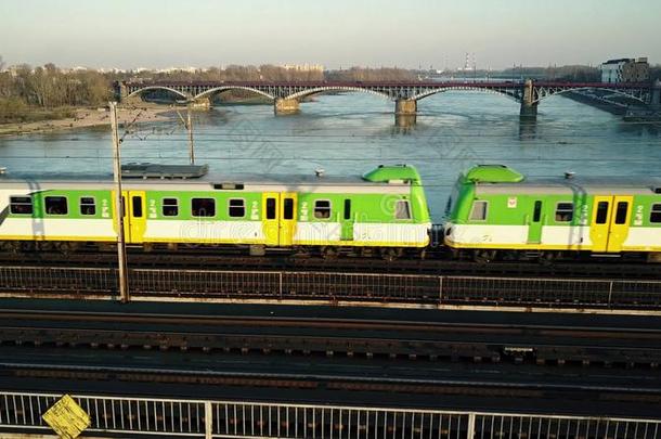 空中拍摄的绿色和黄色客车在铁路桥上穿过河流