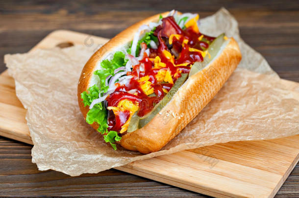 大美味的热狗，酱汁和蔬菜在羊皮纸上的木制背景。 热狗美食家。