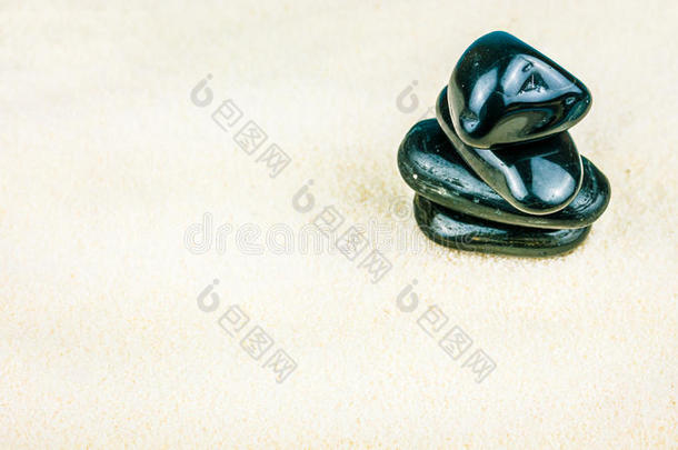在明亮的白沙上堆积着四个黑色的鹅卵石