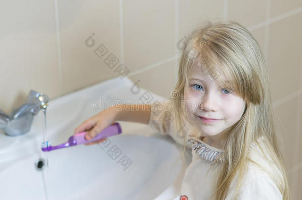 浴室里的女孩洗<strong>电动牙刷</strong>。