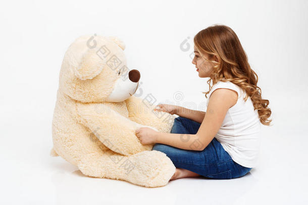女孩和玩具熊说话，因为它是一个朋友。