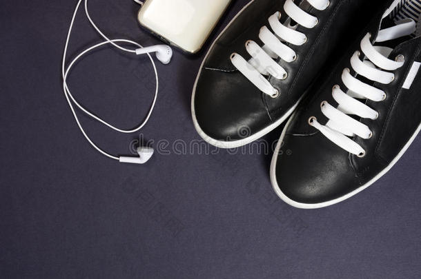 黑色运动鞋与白色鞋带和耳机在黑暗的背景