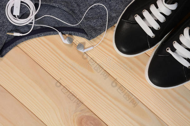 黑色运动鞋，白色鞋带和耳机在木制背景