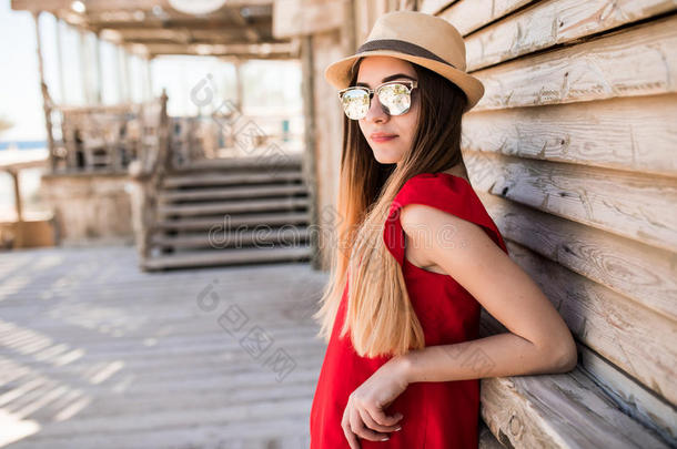 美丽的女<strong>模特</strong>穿着红色的衣服，戴着帽子和太阳镜在避暑胜地。 暑<strong>假</strong>。