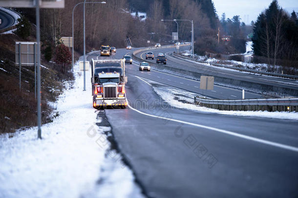 大型钻机半卡车，灯光在路边的冬季雪公路出口