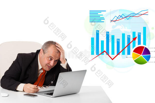 坐在办公桌旁，拿着笔记本电脑和统计数据的商人