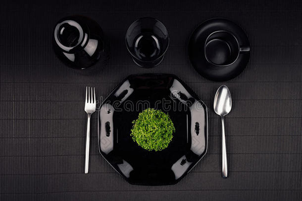 生态黑暗现代简约餐厅菜单模拟黑色光泽板，勺子，叉子，杯子和绿色植物，顶部视图