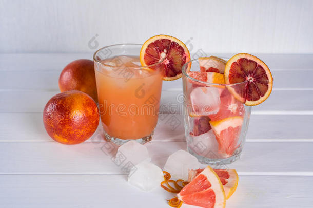 全杯葡萄柚汁和一杯切片水果。 西柚西西里橘子加冰。
