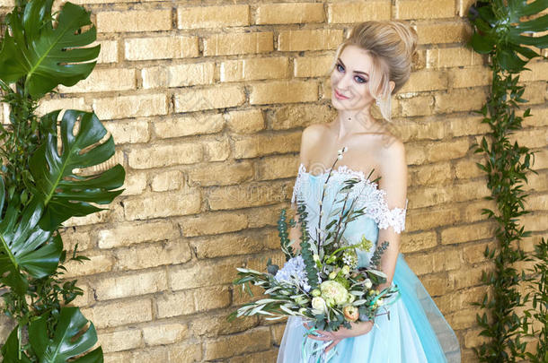 新娘穿着一件漂亮的绿松石连衣裙，期待着婚礼。 金色的蕾丝连衣裙，海绿色的，带花束。 快乐的新娘