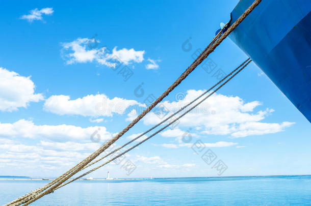 蓝色的船`蓝天背景上的鼻子。 船`的绳子。 美丽的云彩。 地平线上的灯塔。