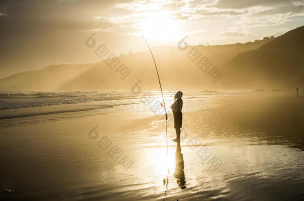 渔民与钓鱼杆持有人在日落在荒野