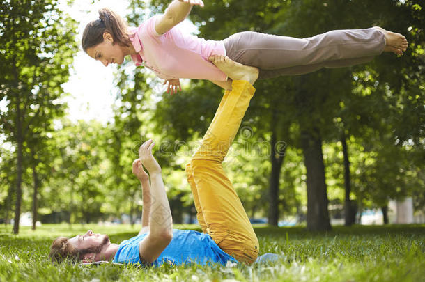一对可爱的夫妇在阳光明媚的一天在公园里做阿克罗瑜伽