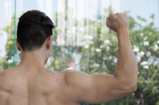 英俊的男人在健身房或健身中心展示肌肉手臂，健康的概念