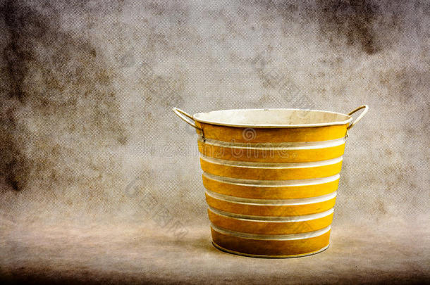 一种黄色和白色条纹金属桶，背景为棕色、纹理