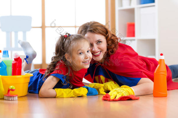 可爱的母亲和她的孩子女儿穿得像超级英雄，打<strong>扫地</strong>板，微笑