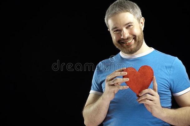 穿着蓝色T恤的开朗胡须男人有一个红色的心形。 爱情，单身，浪漫，约会，关系概念