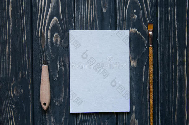 艺术和工艺工具。艺术家的画笔、画布、深色乡村背景上的调色刀